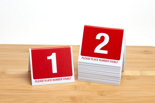 3" tall plastic table number tents. Table numbers feature bold white numbers on a red background. Ideal for use in the restaurant and foodservice industry.